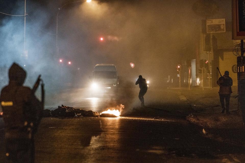 A South Africa Police Service (SAPS) officer aims his rifle at a in incoming minivan bringing it to a stop in Jeppestown, Johannesburg, July 12, 2021, during clashes with residents of the Wolhuter Men's Hostel amid widespread looting and riots in the region. / Credit: MARCO LONGARI/AFP/Getty