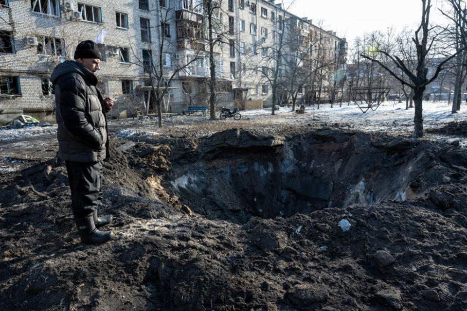 A man looks into the crater of a Russian missile that slammed into a residential area overnight on February 17, 2023 in Lyman, Ukraine. (Scott Peterson/Getty Images)