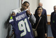 The parents of Seattle Seahawks 2024 first-round NFL football draft pick Byron Murphy II, Bryon Murphy Sr., left, and mother Seneca Murphy, second from left, look at their son's jersey after a news conference at the team's headquarters Thursday, May 2, 2024, in Renton, Wash. (AP Photo/John Froschauer)