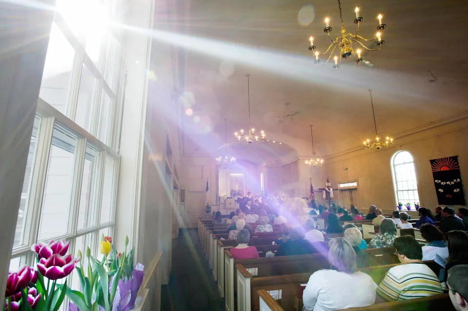 Sunlight streams through a church window during an Easter morning service.