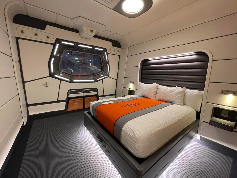 Starcruiser room with a lit-up bed and space-ship like white walls