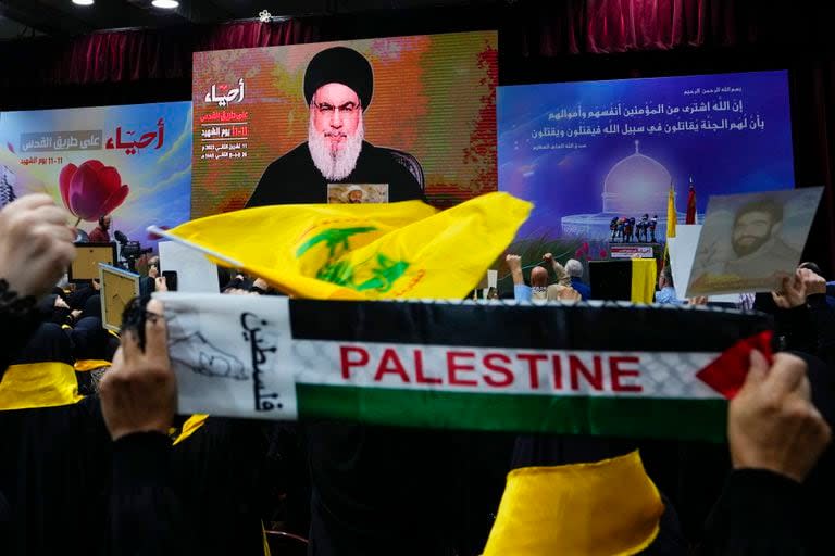 Partidarios de la milicia Hezbollah saludan con el puño en alto al escuchar un discurso del dirigente Hassan Nasrallah  por video en el 