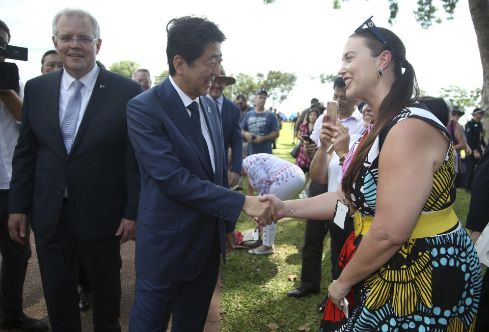 Japan's Prime Minister Shinzo Abe, center, shakes hands with a woman as he walks with Australian Prime Minister Scott Morrison, left, after they laid wreaths at the Cenotaph War Memorial in Darwin, Friday, Nov. 16, 2018. Abe is on a two-day visit to Australia. (AP Photo/Rick Rycroft, Pool)