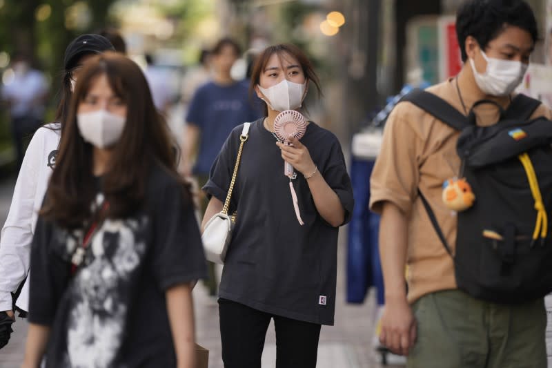 2022年6月27日，日本東京，一名女子帶著手持小風扇走在街頭（美聯社）