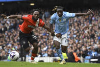 Luton Town's Fred Onyedinma, left, challenges for the ball with Manchester City's Jeremy Doku during the English Premier League soccer match between Manchester City and Luton Town at Etihad stadium in Manchester, England, Saturday, April 13, 2024. (AP Photo/Rui Vieira)
