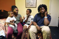 Ida Cartlidge, second from left, holds her youngest son Nolan while sitting with sons Amarii and Jakavien, right, on Nov. 29, 2023, in the middle of their two-bed motel room that serves as their temporary residence after a deadly tornado destroyed their home in March. The Cartlidge family of five spent nearly a year in the cramped motel room in search of a more permanent home, like many of their displaced neighbors. (AP Photo/Rogelio V. Solis)