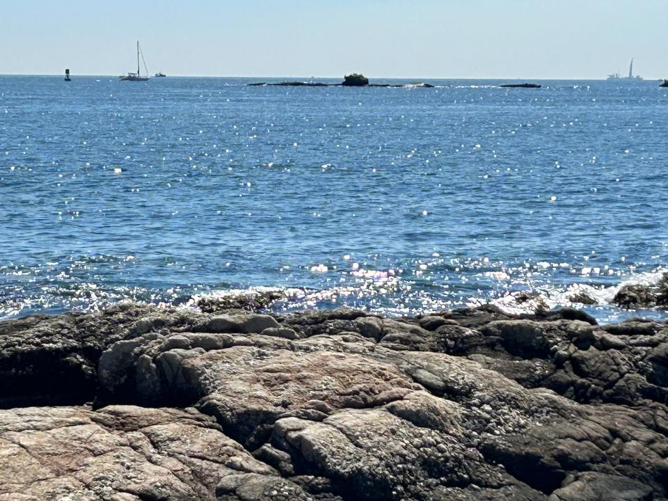 Whale Rock est visible au loin, à environ 800 mètres au large. La base de son ancien phare, détruit lors de l'ouragan de 1938, est toujours là, dépassant des rochers plats.