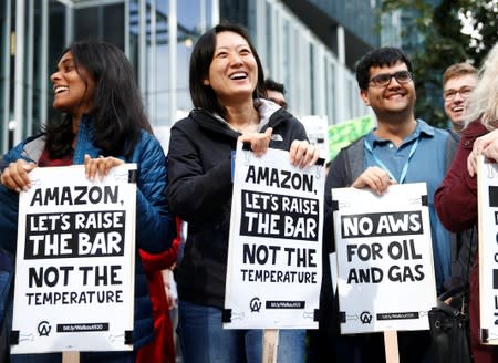 Amazon employees Preethy Thomas and Yuan Dong smile as they hold signs during a Climate Strike march and walkout at the Amazon Spheres in Seattle