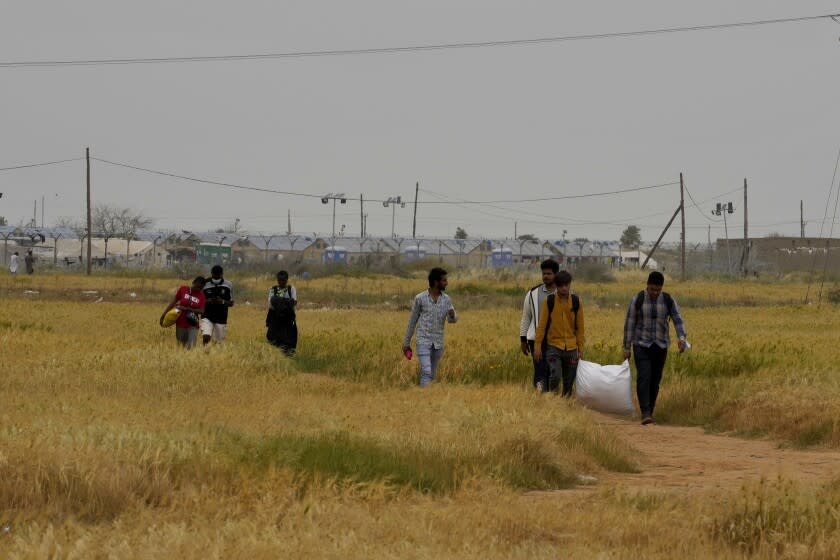 FILE - Migrants walk near the Pournara Emergency Reception center, in Kokkinotrimithia, on the outskirts of the capital Nicosia, Cyprus, April 18, 2022. Breakaway Turkish Cypriots on ethnically-divided Cyprus must do their share in stemming migrant arrivals, a senior European Union official said Saturday June 18, 2022, as the number of asylum-seekers has shot up significantly so far this year. (AP Photo/Petros Karadjias, File)