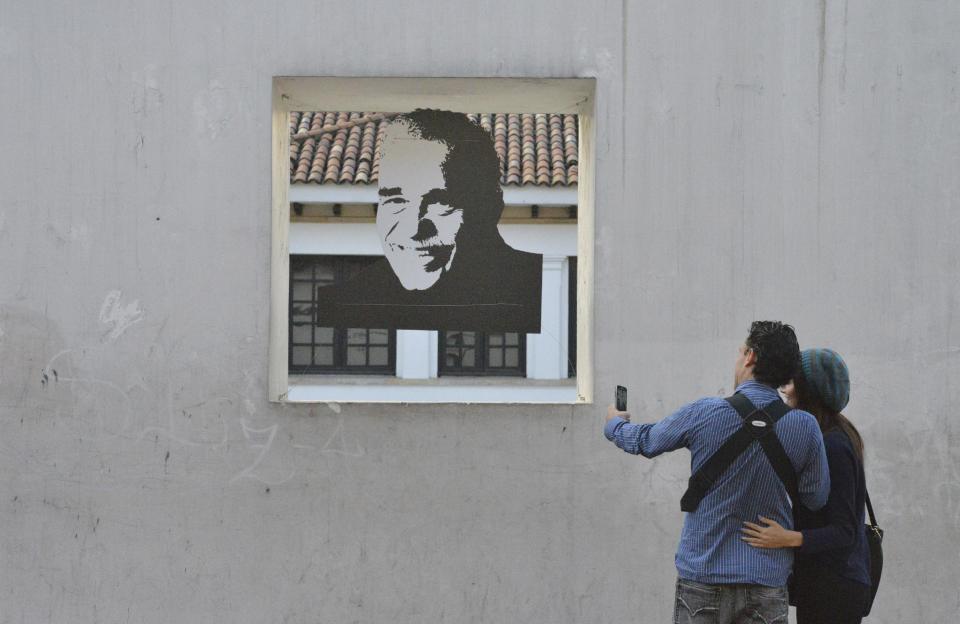 Una pareja toma una fotografía de un retrato del autor colombiano Gabriel García Márquez frente al Museo Casa de Moneda en el centro de Bogotá, Colombia. El jueves el jueves 17 de abril de 2014. García Márquez murió en su casa en la Ciudad de México el jueves. El fallecimiento del autor de “Cien años de soledad” sumió en el dolor a millones de lectores que conocieron Latinoamérica gracias a su obra. (Foto AP/Diana Sanchez)