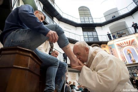 FILE PHOTO: Pope Francis kisses the foot of an inmate at the Regina Coeli prison during the Holy Thursday celebration in Rome, Italy, March 29, 2018. Vatican Media/Handout via REUTERS/File photo