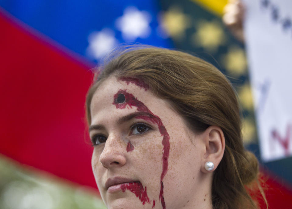 An anti-government demonstrator, with a bleeding bullet hole drawn on her forehead, takes part in a protest in front of an office of the Organization of American States, OAS, in Caracas, Venezuela, Friday, March 21, 2014. Opposition lawmaker Maria Corina Machado is scheduled to speak before the OAS council in a closed-door session Friday in Washington D.C., presenting the situation in her country where at least 28 people have been killed in daily anti-government protests that began in early February. (AP Photo/Esteban Felix)