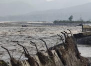 A rescue team delivers rations and essential supplies to Chukum village across the flooded Kosi river, with the broken retaining wall of the Lemon Tree hotel seen on right, in Uttarakhand state, India, Wednesday, Oct. 20, 2021. At least 46 people have died and several are missing after floods triggered by heavy rains hit the northern Indian state of Uttarakhand, officials said Wednesday. (AP Photo/Mustafa Quraishi)