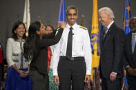 FILE - Then Vice President Joe Biden, right, watches as U.S. Surgeon General Vivek Murthy, center, receives an epaulet on his uniform by his sister Rashmi Murthy during a ceremonial swearing in ceremony in Conmy Hall at Fort Myer in Arlington, Va. on April 22, 2015. Murthy, the country's top public health watchdog, warned that widespread loneliness in the U.S. poses health risks as deadly as smoking up to 15 cigarettes a day. (AP Photo/Andrew Harnik, File)