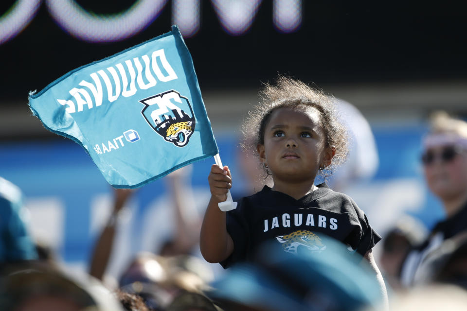 A Jacksonville Jaguars fan waves a flag during the second half of an NFL football game against the Arizona Cardinals, Sunday, Sept. 26, 2021, in Jacksonville, Fla. (AP Photo/Stephen B. Morton)