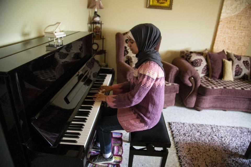 Yara plays her piano which took three years to get into Gaza and cost thousands of dollars (Photo: Bel Trew)