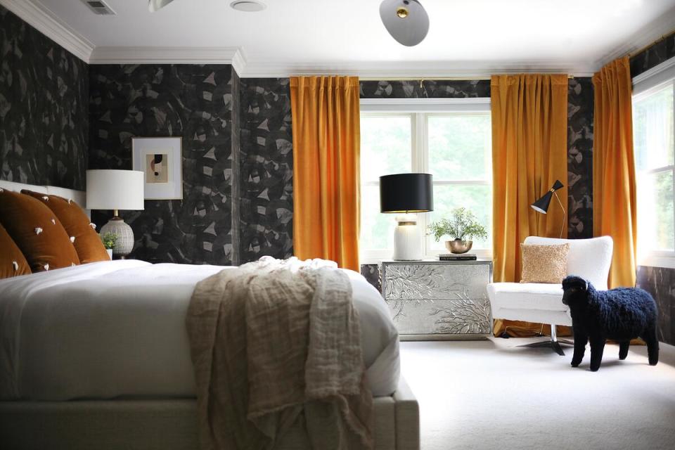 A bedroom by House Of Hipsters with gray patterned wallpaper and orange accents