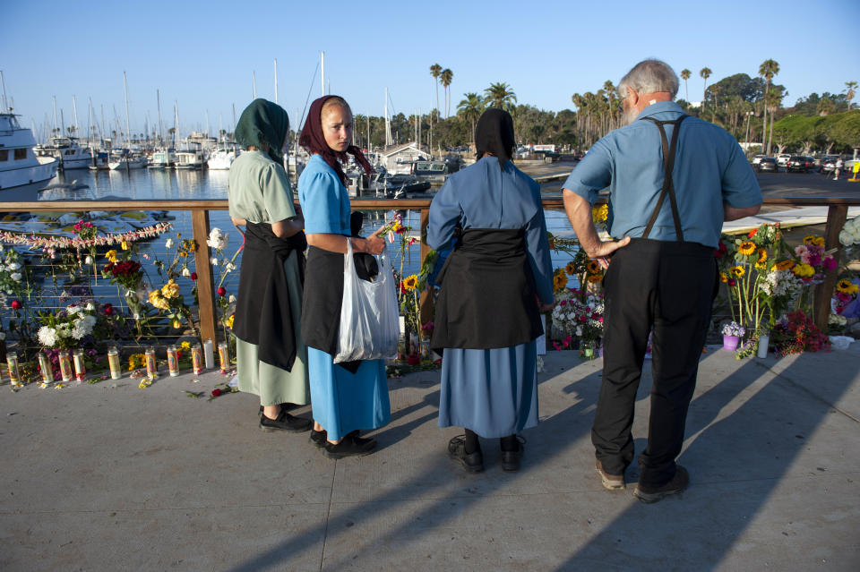 A family from Iowa observes a memorial placed for the victims of Monday's dive boat fire at the Santa Barbara Harbor on Wednesday, Sept. 4, 2019, in Santa Barbara, Calif. (AP Photo/Christian Monterrosa )