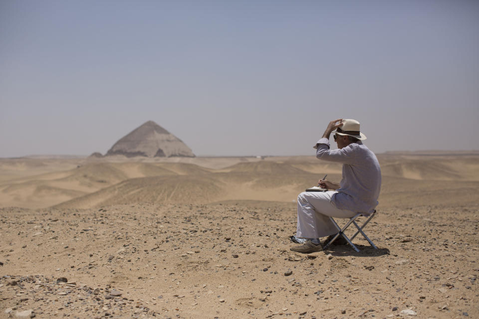 A member of an international delegation sketches the site of the Bent Pyramid during an event opening the pyramid and its satellites for visitors in Dashur, Egypt, Saturday, July 13, 2019. The Bent pyramid, listed on UNESCO's world heritage list as part of the Memphis necropolis, is considered a transition phase in pyramids construction that comes between step pyramids and complete pyramids. (AP Photo/Maya Alleruzzo)