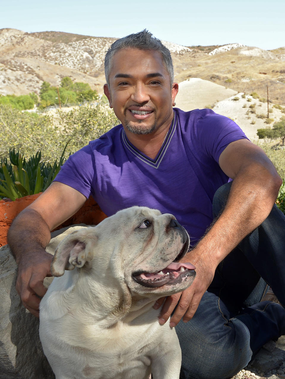 In this Oct. 18, 2012 photo, Cesar Millan poses with his English Bull Dog George at his Dog Psychology Center, in Santa Clarita, Calif. Millan has a new television show, book, tour and documentary. "Cesar Millan: The Real Story" airs on Nat Geo Wild on Nov. 25, 2012. It will also launch a global speaking tour. (AP Photo/Mark J. Terrill)