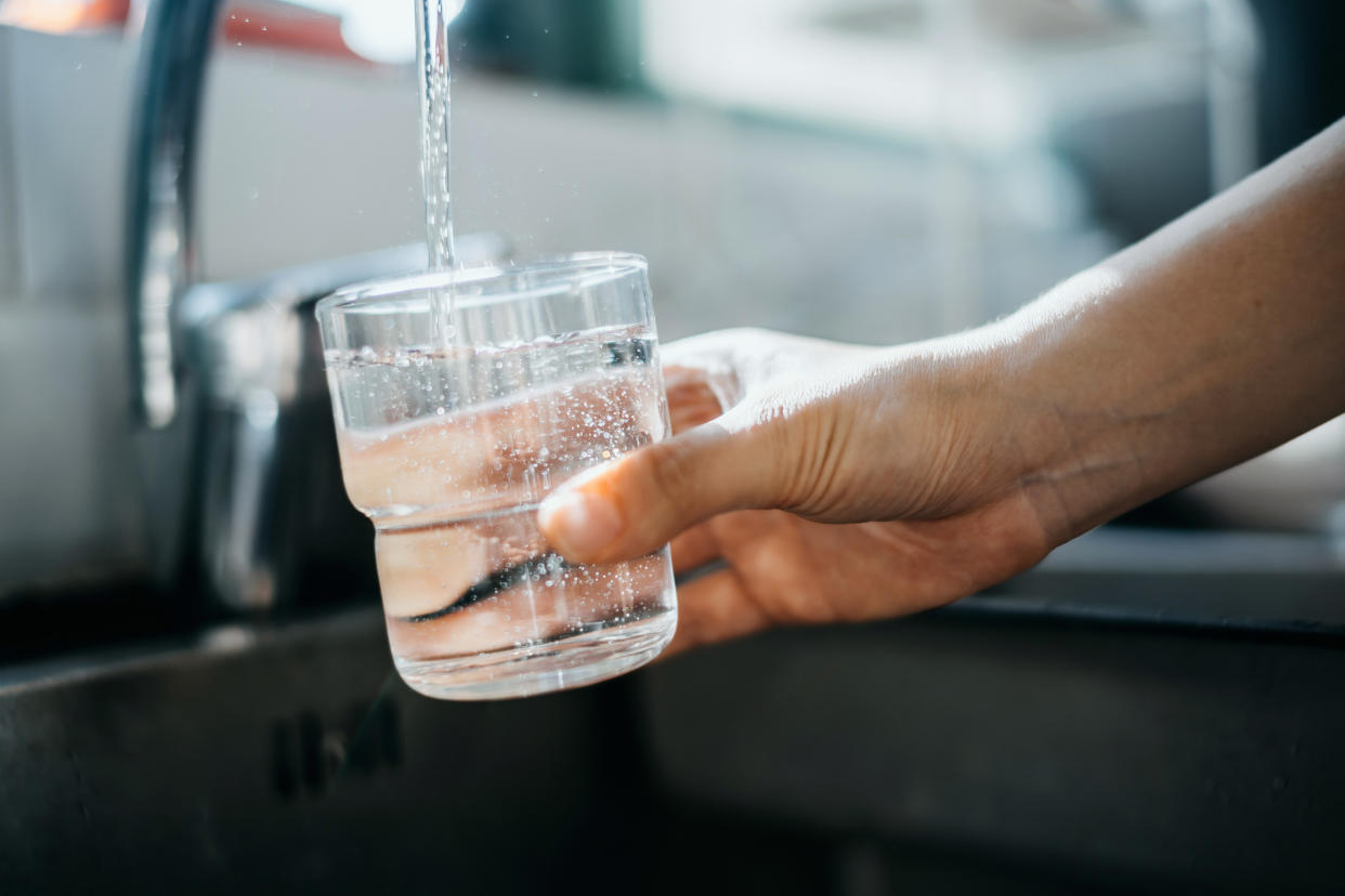 Water running from a faucet into a drinking glass.