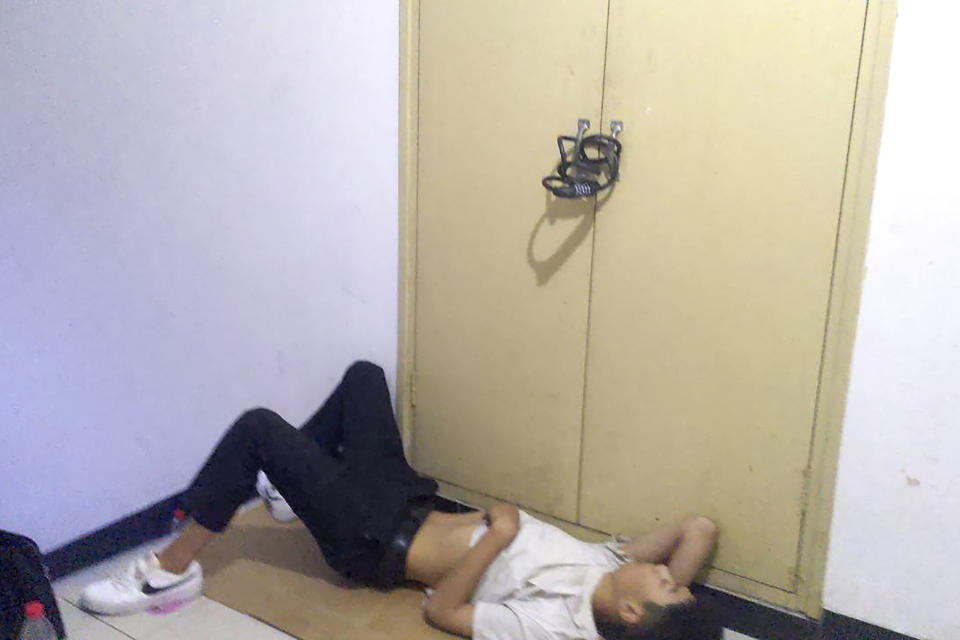 In this photo released by Wang Quanzhang, an unidentified man sleeps near the locked electrical box outside his apartment where power has been cut in Beijing's Changping district, on June 19, 2023. Disbarred human rights lawyer Wang Quanzhang has been forced to move 13 times in two months as part of a pattern of harassment against him and three other prominent rights advocates in Beijing that is further squeezing the country's battered civil rights community. (Wang Quanzhang via AP)