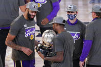 Los Angeles Lakers' Anthony Davis, left, looks at their trophy after beating the Denver Nuggets in an NBA conference final playoff basketball game Saturday, Sept. 26, 2020, in Lake Buena Vista, Fla. The Lakers won 117-107 to win the series 4-1. (AP Photo/Mark J. Terrill)