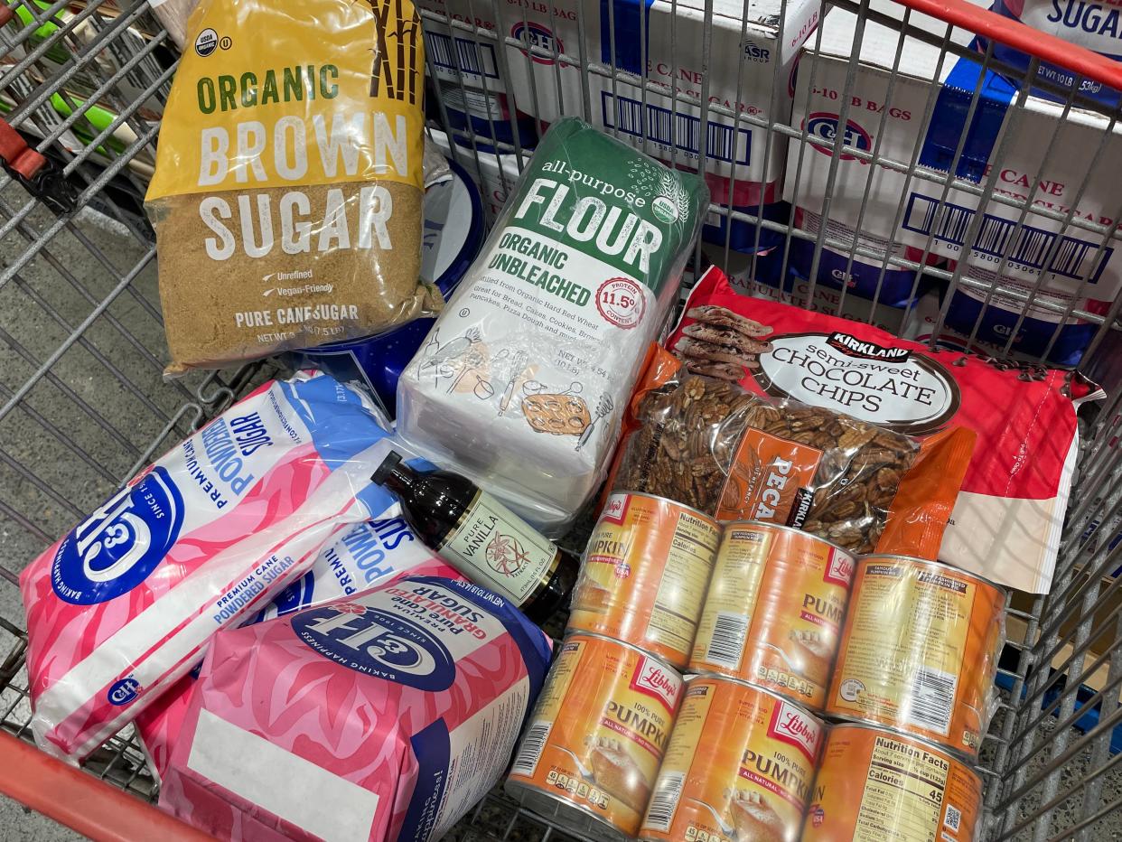 Costco cart full of baking supplies, like flour, brown sugar, and canned pumpkin