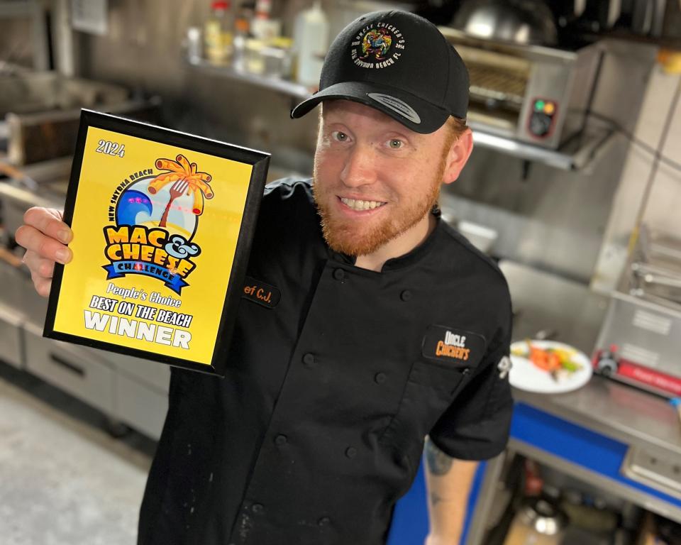 Owner Craig Glore Jr. holds plaque celebrating Uncle Chicken's first place win at the 2024 New Smyrna Beach Mac & Cheese Challenge.