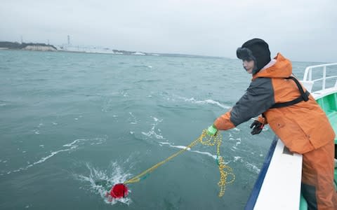  Kaori Suzuki, manager of NPO Tarachine, casts a bucket into the Pacific Ocean to collect seawater samples about a mile from the Fukushima No. 2 Nuclear Power Plant - Credit: Simon Townsley