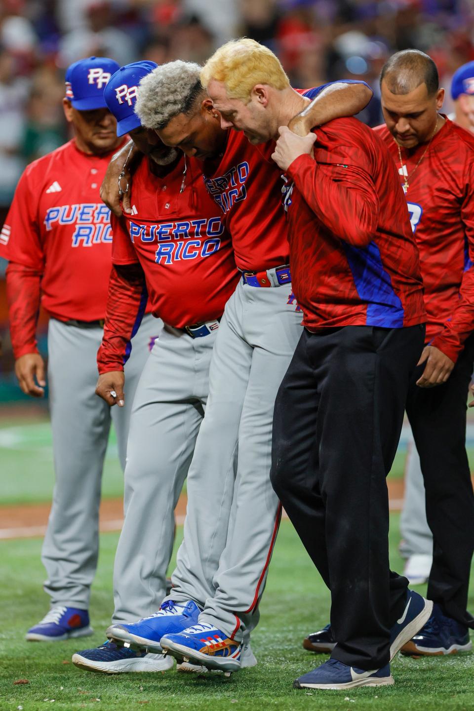 Edwin Diaz is helped off the field after he injured his knee during Puerto Rico's celebration against the Dominican Republic.