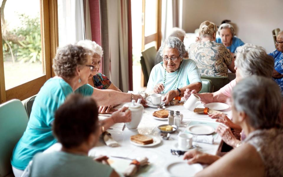 A group of seniors enjoying breakfast together in their retirement home - shapecharge  