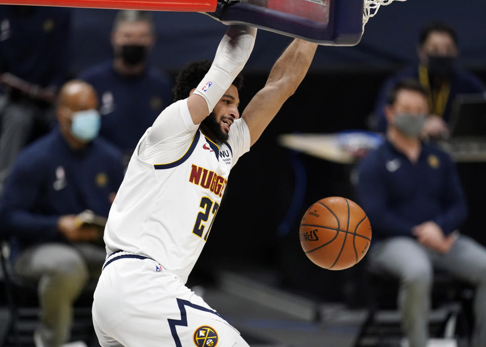 Denver Nuggets guard Jamal Murray hangs from the rim after dunking against the Utah Jazz in the second half of an NBA basketball game Sunday, Jan. 31, 2021, in Denver. (AP Photo/David Zalubowski)