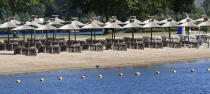 Parasols wait for tourists on a hot summer day at a lake in Xanten, Germany, Thursday, May 28, 2020. Germany's states, which determine their own coronavirus-related restrictions, have begun loosening lockdown rules to allow domestic tourists to return. (AP Photo/Martin Meissner)