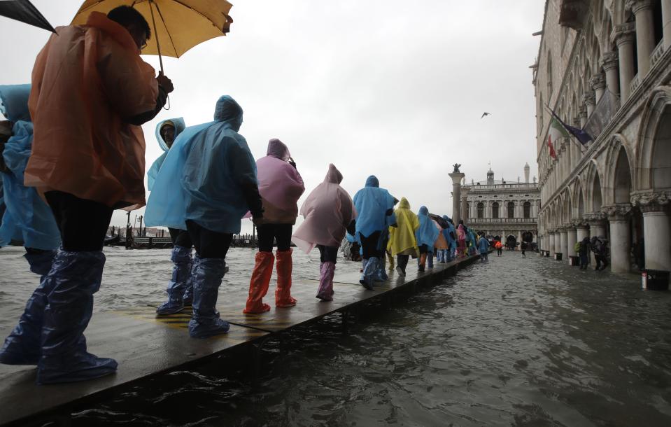 People walk on catwalk set up on the occasion of a high tide, in a flooded Venice, Italy, Tuesday, Nov. 12, 2019. (Photo: Luca Bruno/AP)