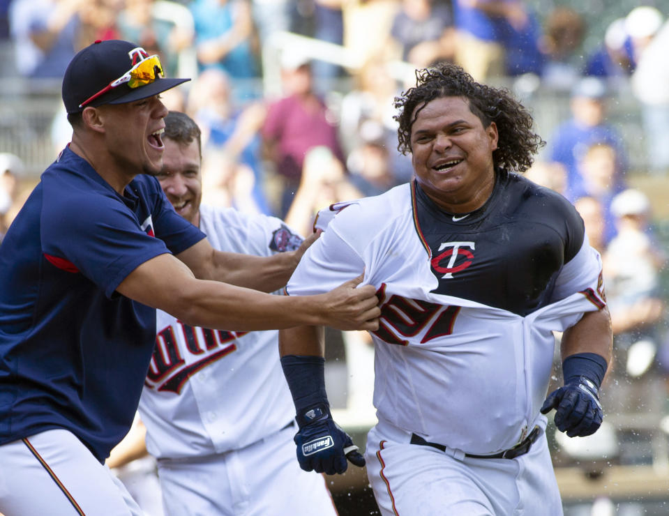 FILE - In this Sept. 9, 2018, file photo, Minnesota Twins' Willians Astudillo, right, is mobbed by teammate Jose Berrios after hitting a 2-run home run during the ninth inning of a baseball game against the Kansas City Royals, in Minneapolis. The most popular player on the first-place Minnesota Twins is the third-string catcher and versatile everyman Willians Astudillo, whose all-out style has endeared him to the team and the fans since his debut last season. His cult hero status reaches a new high on Friday night, when the Twins give away La Tortuga T-shirts in honor of his nickname, which means turtle in Spanish, at their game against Baltimore. (AP Photo/Paul Battaglia, File)
