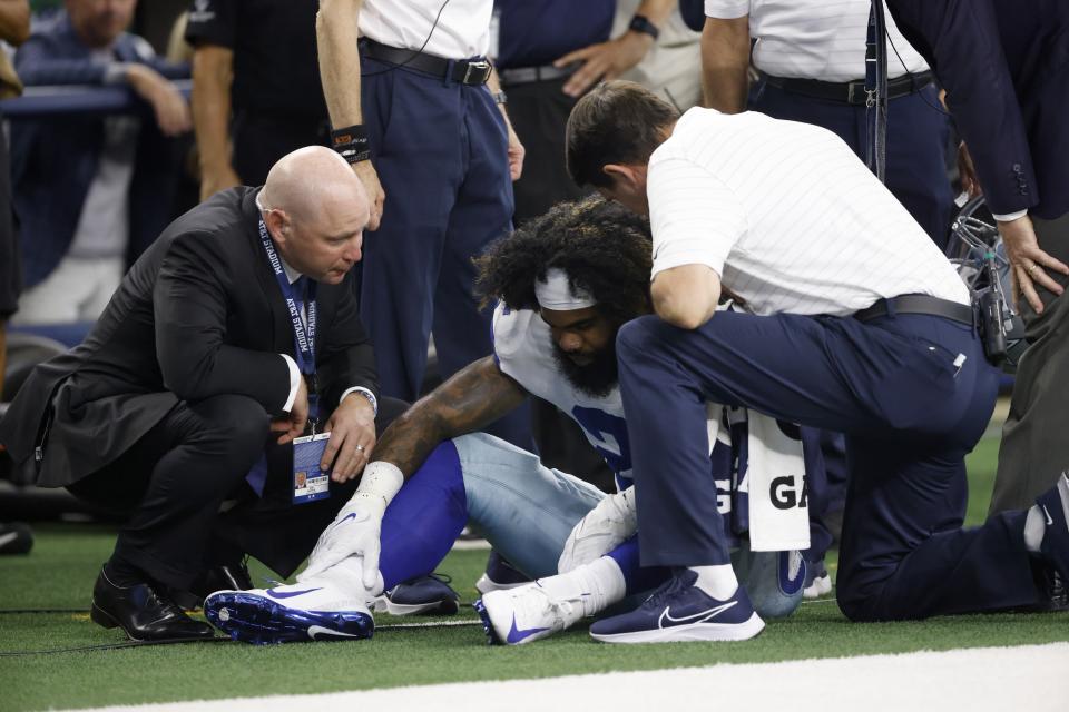 Dallas Cowboys running back Ezekiel Elliott (21) is checked by team staff after he carried the ball for a gain in the second half of an NFL football game in Arlington, Texas, Sunday, Oct. 10, 2021. Elliott continued playing in the game. (AP Photo/Ron Jenkins)