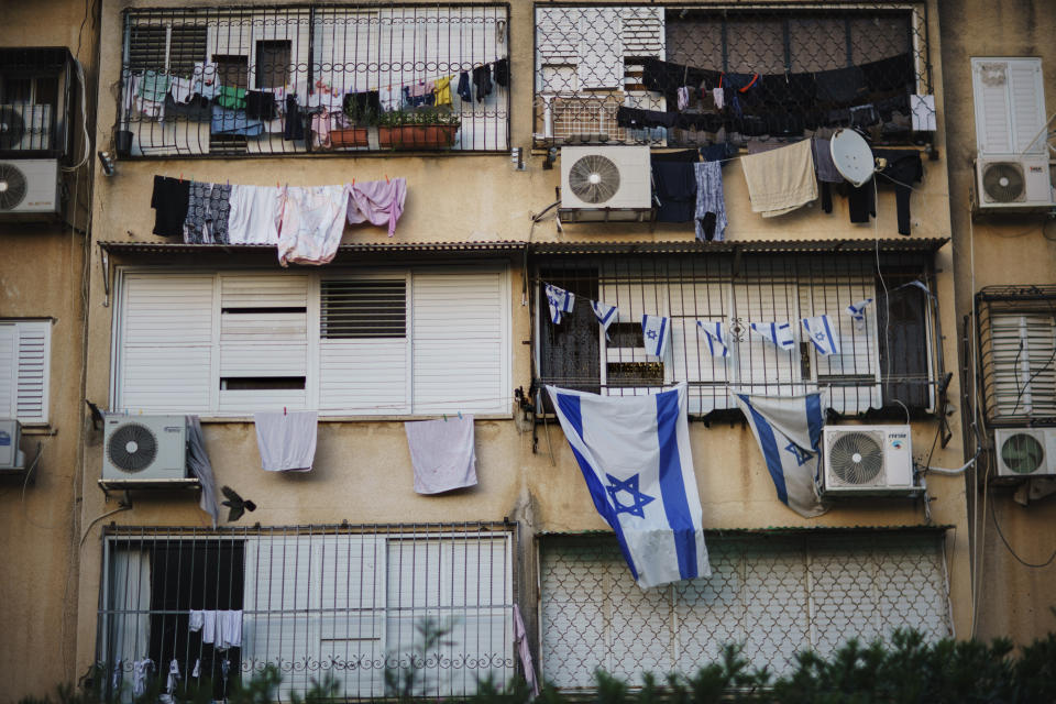 Israeli flags hang outside an apartment of a Jewish family at a building where Arab families also live in the Ramat Eshkol neighborhood in the mixed Arab-Jewish town of Lod, central Israel, Friday, May 28, 2021. An urban landscape of low-rise housing projects from the 1950s and '60s, the working-class city also is a bastion of hard-line Jewish politics. (AP Photo/David Goldman)