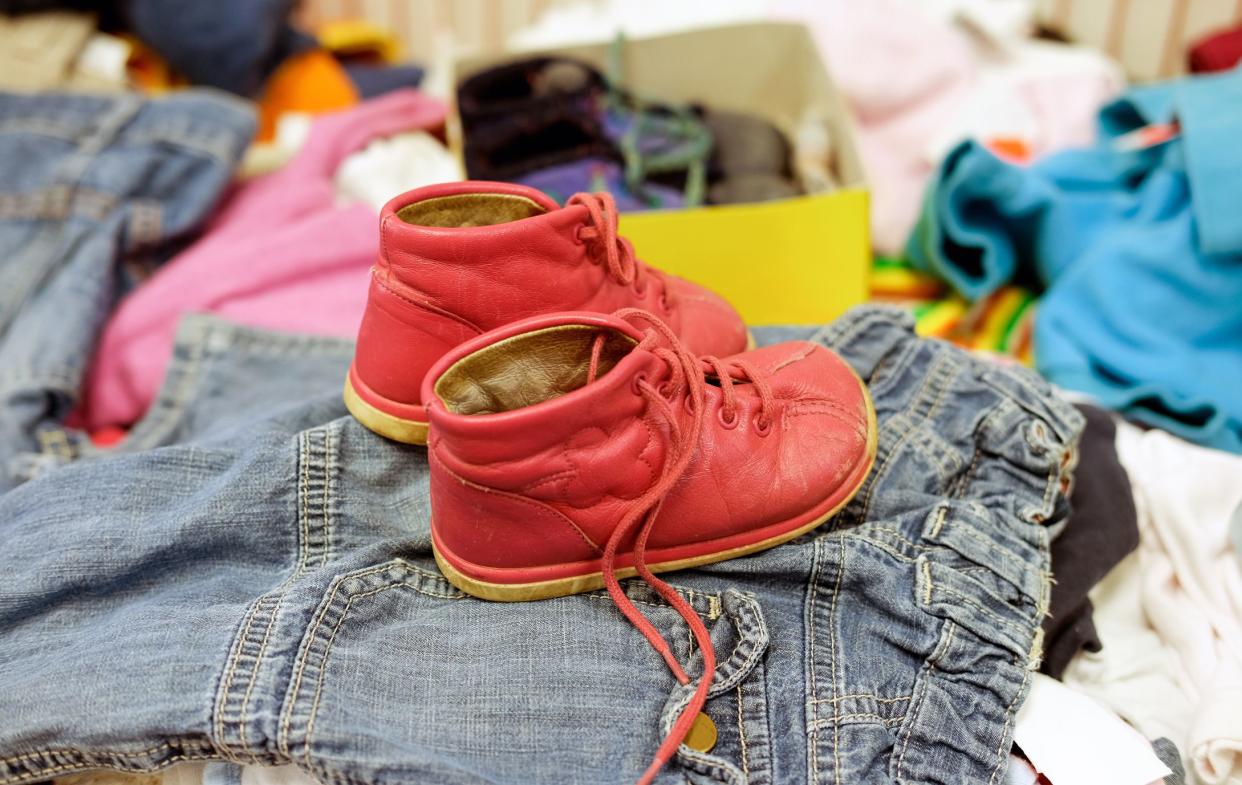 Social care, poverty concept: Used red shoes for young children in a thrift shop between other used clothes