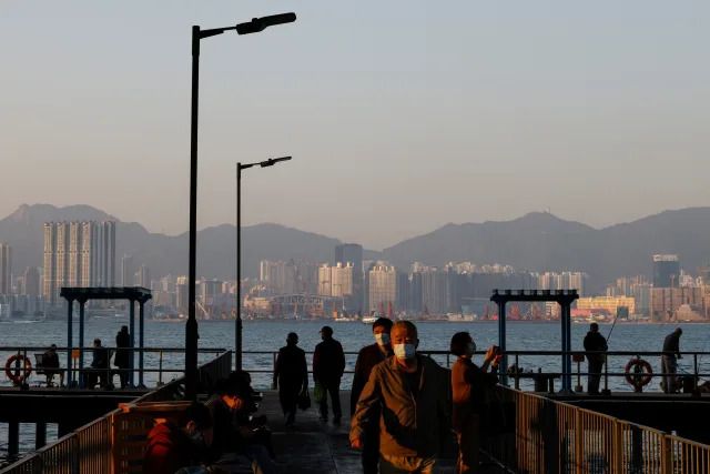 Elderly men wearing face masks walk at a shore in Hong Kong, China, February 17, 2023. REUTERS/Tyrone Siu