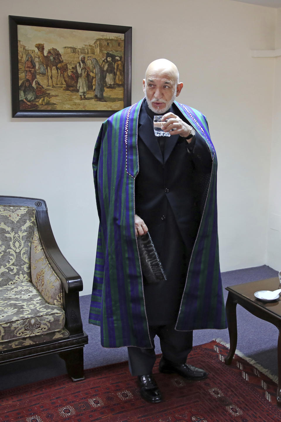 Former Afghan President Hamid Karzai drinks a glass of water after an interview with The Associated Press, in Kabul, Afghanistan, Tuesday, Dec. 10, 2019. Karzai, whose final years in power were characterized by a cantankerous relationship with the United States, said on Tuesday that Washington used blackmail and corruption to manipulate his officials, undermine his government and foment violence among the country's many factions. (AP Photo/Altaf Qadri)