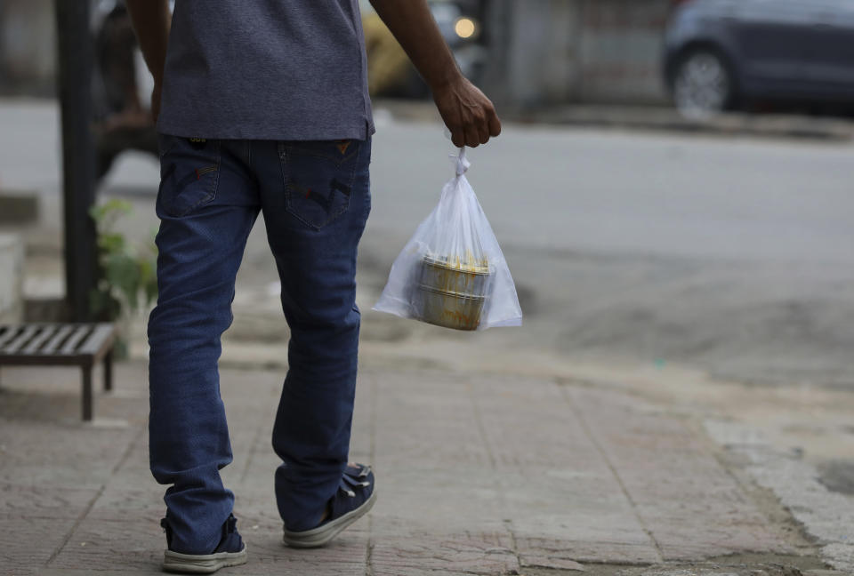 A man carrying his tiffin box in a single use plastic cover walks through a street in Hyderabad, India, Thursday, June 30, 2022. India banned some single-use or disposable plastic products Friday as a part of a longer federal plan to phase out the ubiquitous material in the nation of nearly 1.4 billion people. (AP Photo/Mahesh Kumar A.)