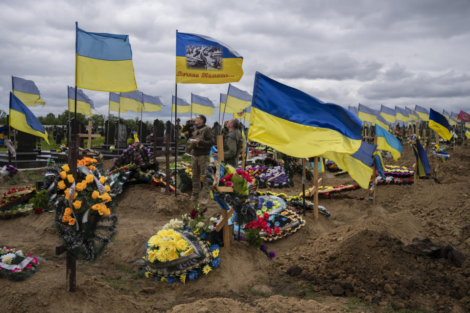 Two national guard soldiers drink a shot to honor the memory of two late soldiers in Kharkiv cemetery, eastern Ukraine, Sunday, May 22, 2022. (AP Photo/Bernat Armangue)