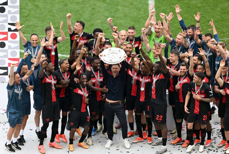 Bayer Leverkusen Coach Xabi Alonso (C) celebrates with the championship trophy following the German Bundesliga soccer match between Bayer Leverkusen and FC Augsburg at BayArena. David Inderlied/dpa