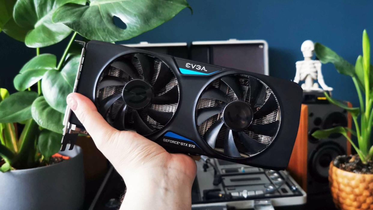  EVGA version of Nvidia GeForce GTX 970 being held with plants in bakcdrop. 