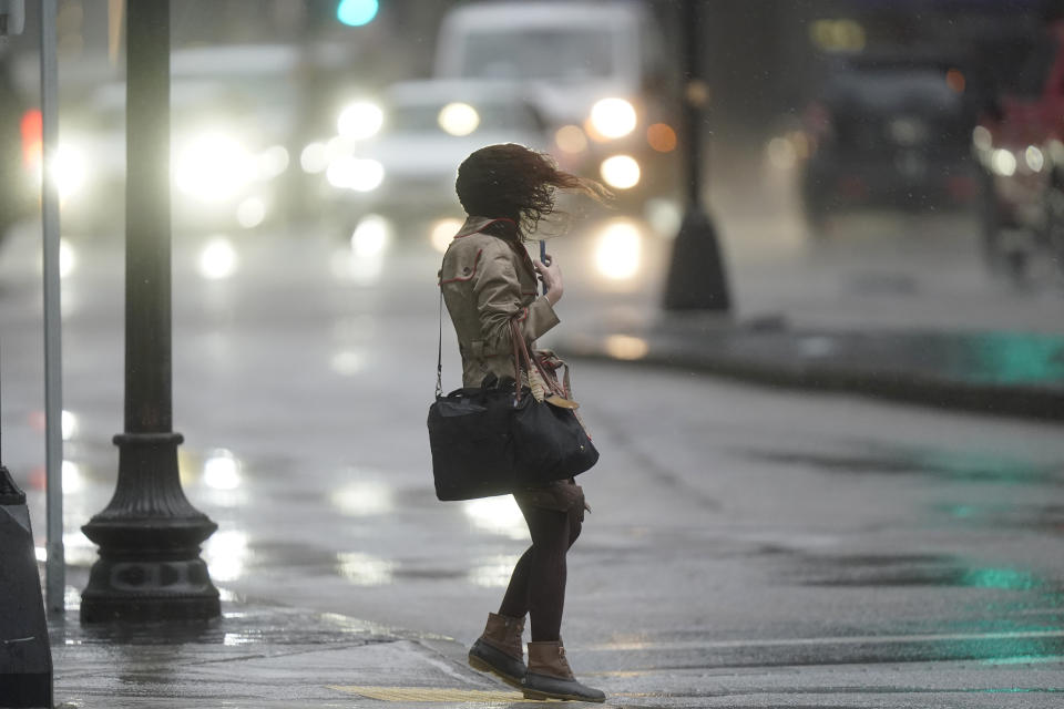 A pedestrian is buffeted by wind and rain while crossing a street, Monday, Dec. 18, 2023, in Boston. A storm moving up the East Coast brought heavy rain and high winds to the Northeast on Monday, threatening flooding, knocking out power to hundreds of thousands. (AP Photo/Steven Senne)
