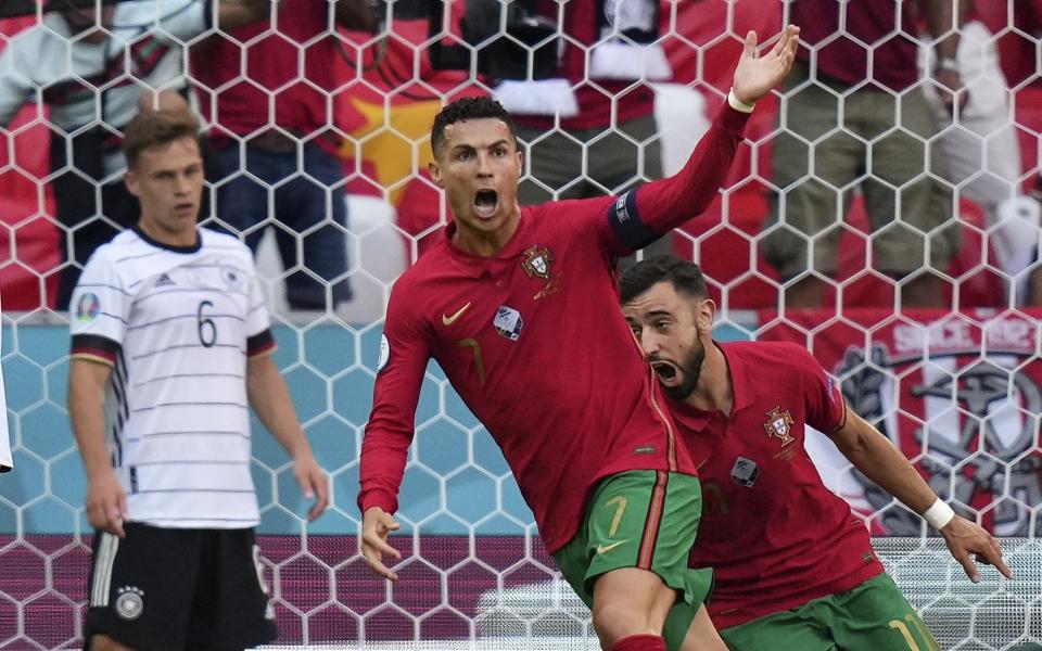 Portugal's Cristiano Ronaldo celebrates beside Germany's Joshua Kimmich, left, after scoring the opening goal during the Euro 2020 soccer championship group F match between Portugal and Germany in Munich, Saturday, June 19, 2021. (AP Photo/Matthias Schrader, Pool)