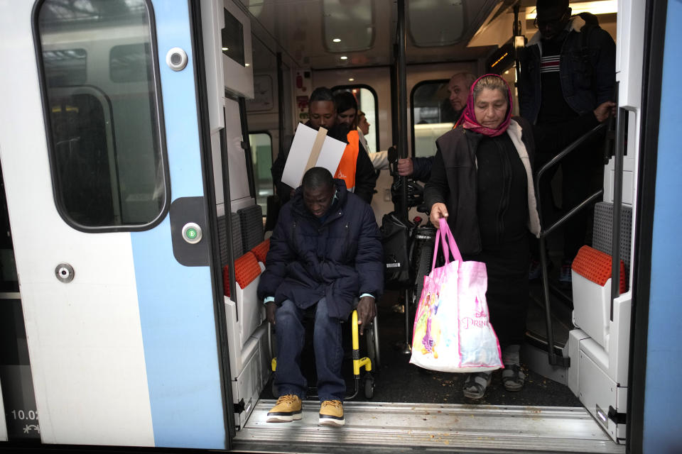 FILE - Babou Sene, left, is helped getting out of a train Wednesday, April 26, 2023 at the Gare de Lyon train station, in Paris. Paris 2024. Organisers insist their preparations remain on track for promised greener-than-ever, safe and inclusive games. (AP Photo/Christophe Ena, File)