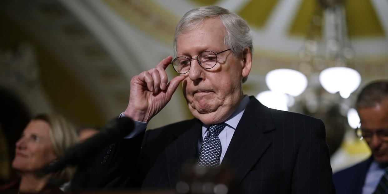 mitch mcconnell adjusts his glasses while standing at a podium