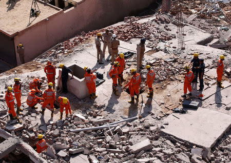 Rescue workers look for survivors amidst the rubble at the site of a collapsed residential building at Shah Beri village in Greater Noida, July 18, 2018. REUTERS/Adnan Abidi